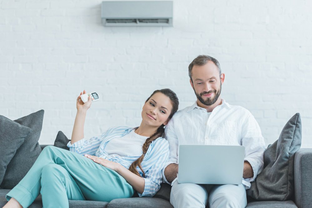 Pareja que enciende el aire acondicionado durante el calor