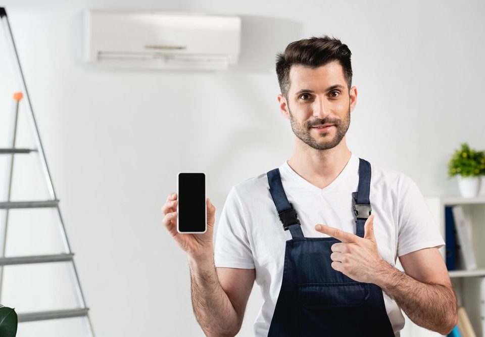 Reparador sonriente apuntando al telefono inteligente